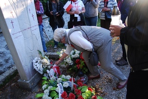Składanie zniczy i kwiatów pod pomnikiem na cmentarzu w Ebensee