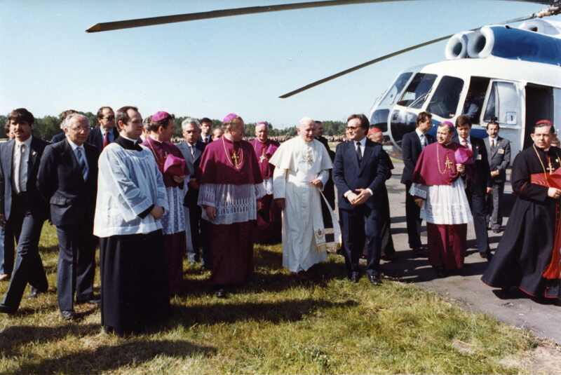 Powitanie Papieża Jana Pawła II w parku na Łęgach Dębińskich w Poznaniu. Jan Paweł II idzie w otoczeniu biskupów i przedstawicieli władz wojewódzkich i miejskich. 20 VI 1983 r. Sygnatura: IPNPo-7-7-2-4